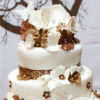 Four-tiered bronze-and-white cake with whimsical flower detailing